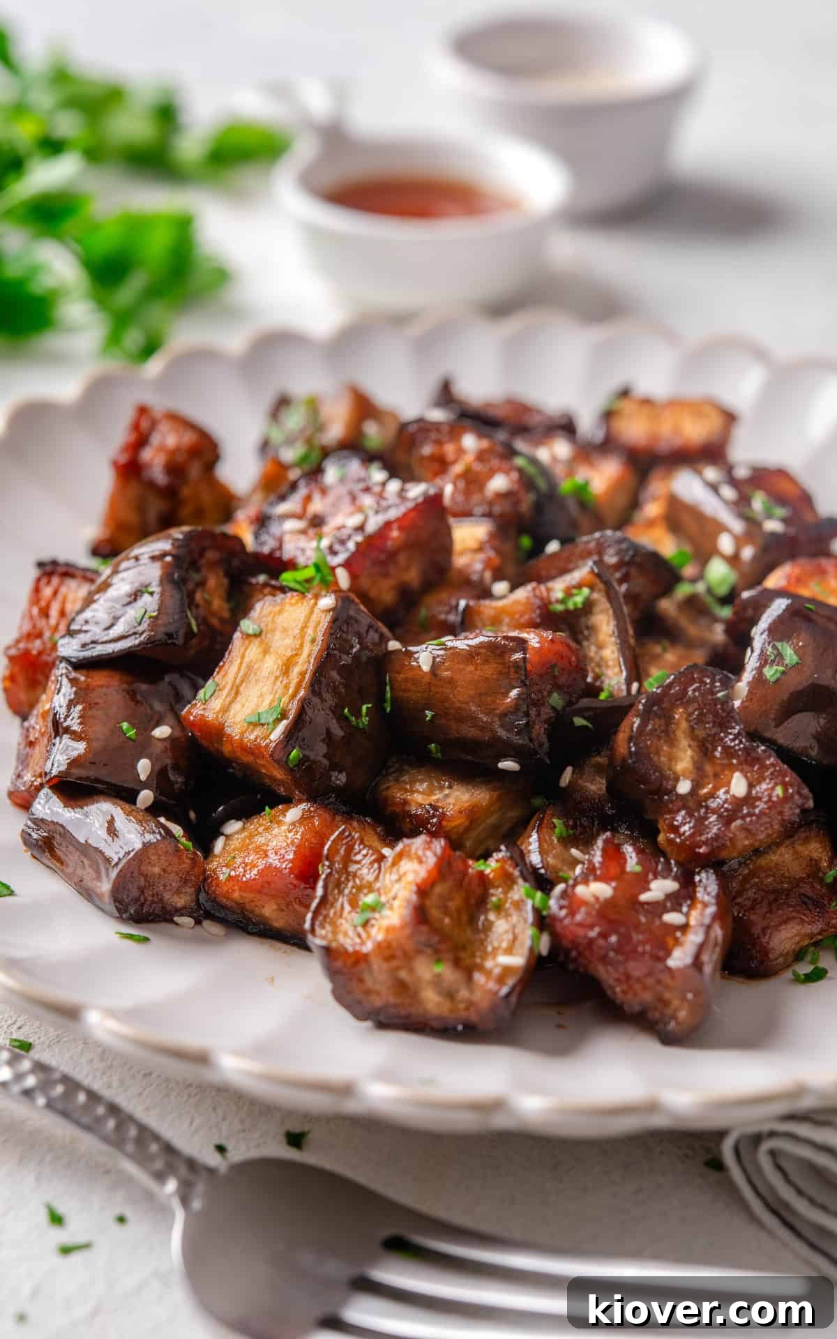 Close-up of roasted aubergine cubes with tamari, garnished with sesame seeds.