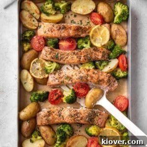 A vibrant salmon traybake with roasted vegetables, including potatoes, broccoli, and cherry tomatoes, garnished with fresh parsley.