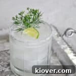 Perfect Margarita with a lime and greenery as a garnish. The lowball glass is sitting on a silver platter.