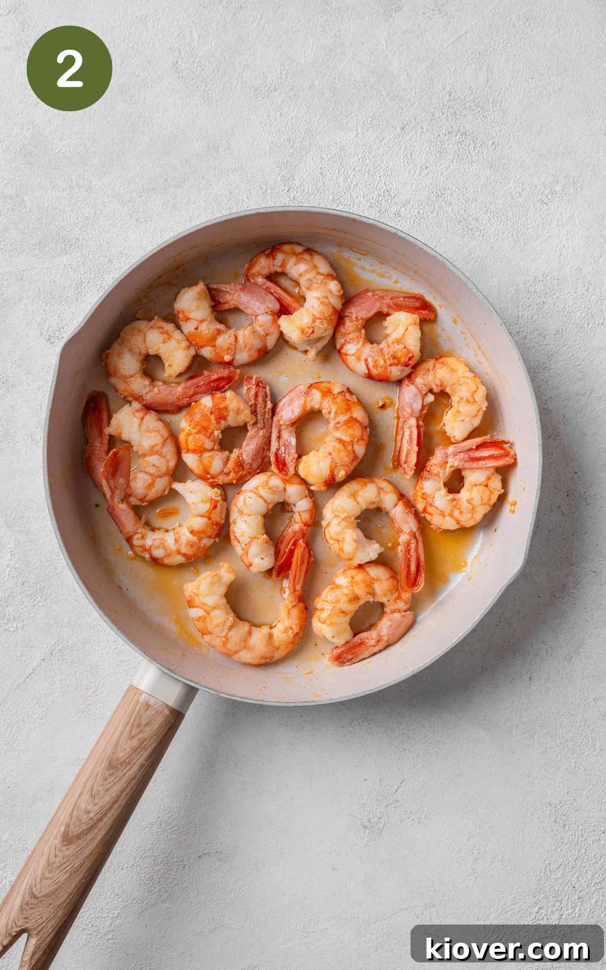 Prawns being pan-fried in olive oil in a large skillet until pink.