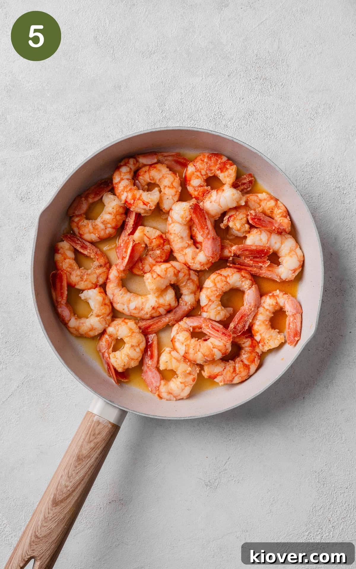 Cooked prawns tossed in the creamy garlic butter sauce in a skillet, ready to serve.