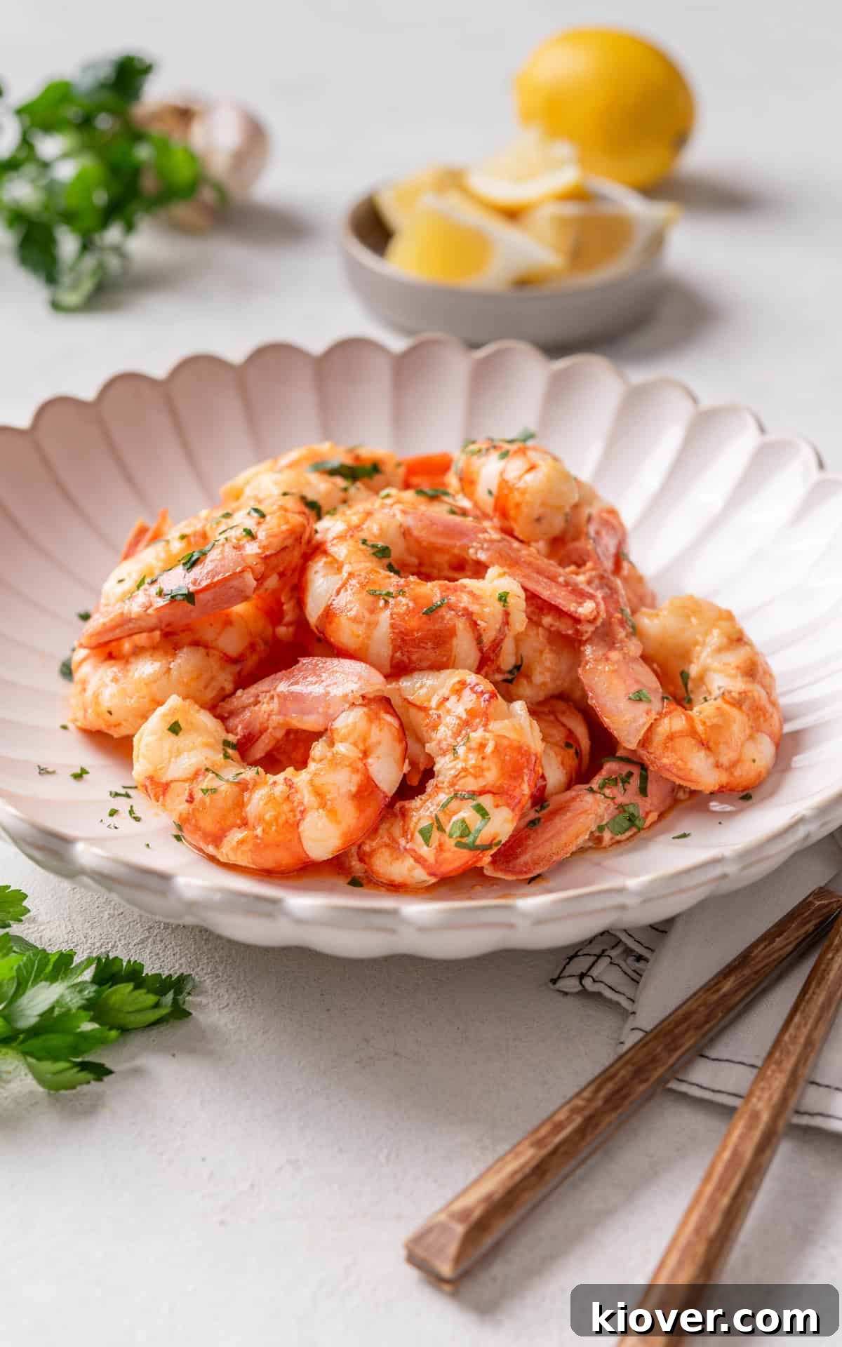 Beautifully plated garlic prawns garnished with freshly chopped parsley and vibrant lemon slices, ready for a gourmet meal.