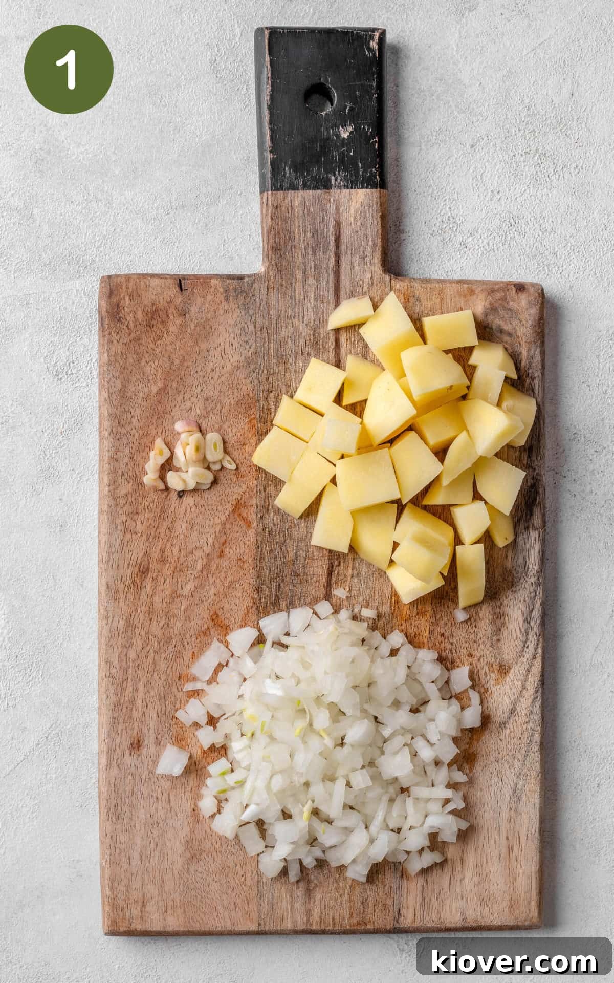 Velvety Spinach Soup 4 Finely chopped onion, thinly sliced garlic, and peeled, cubed potatoes neatly arranged on a wooden chopping board.