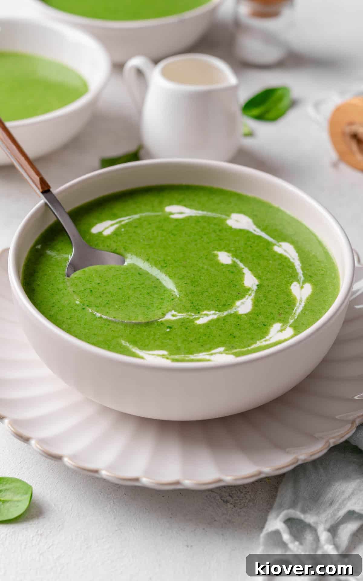 Velvety Spinach Soup 9 A beautifully presented bowl of creamy spinach soup, garnished with a delicate swirl of plant-based cream and a sprinkle of black pepper, ready for serving.