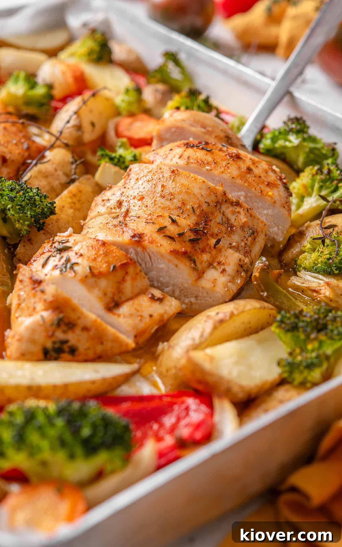 A close-up shot of a perfectly roasted chicken and vegetable traybake, highlighting the golden chicken and vibrant, tender vegetables.