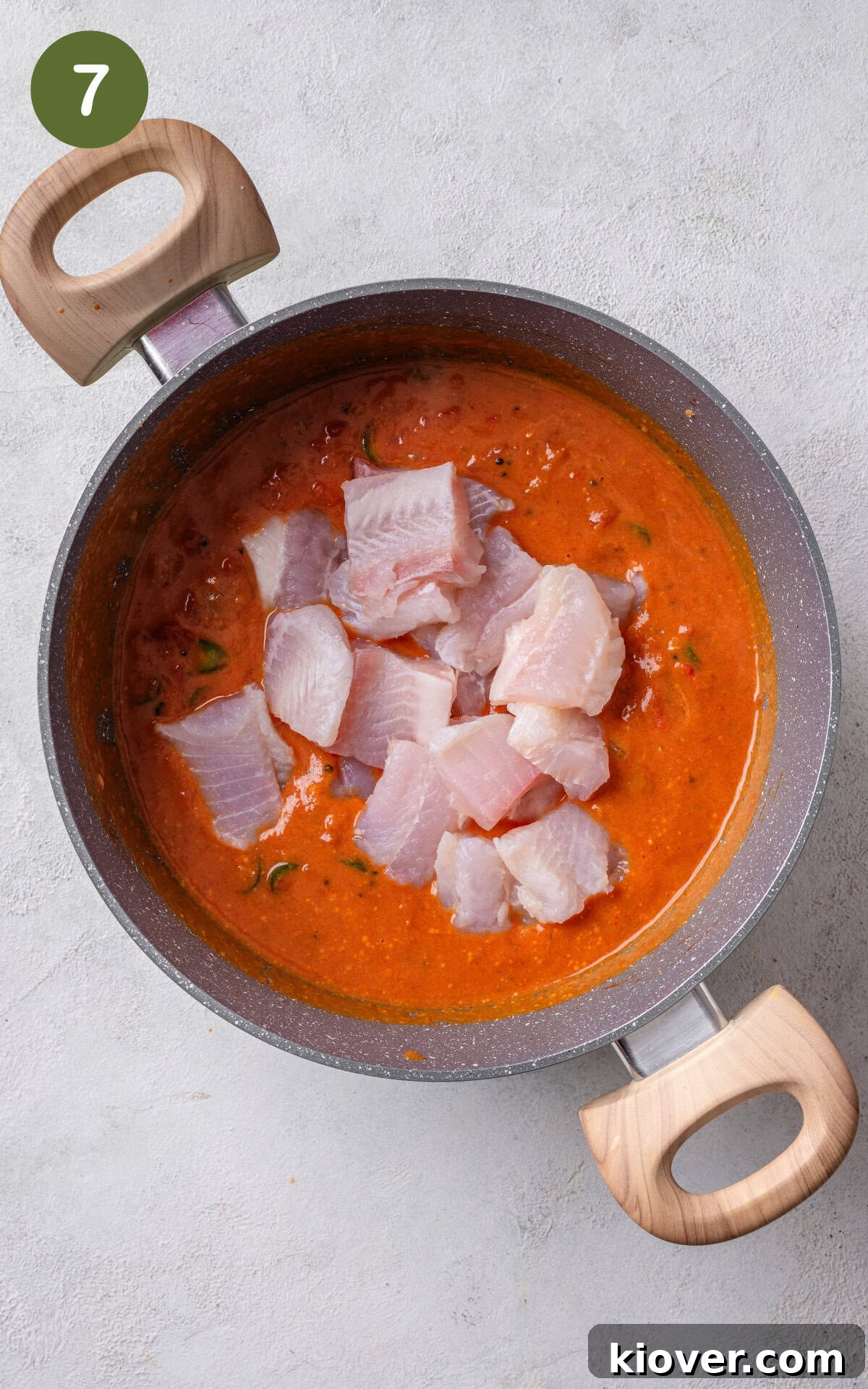 Fish and a curry sauce in a pan.