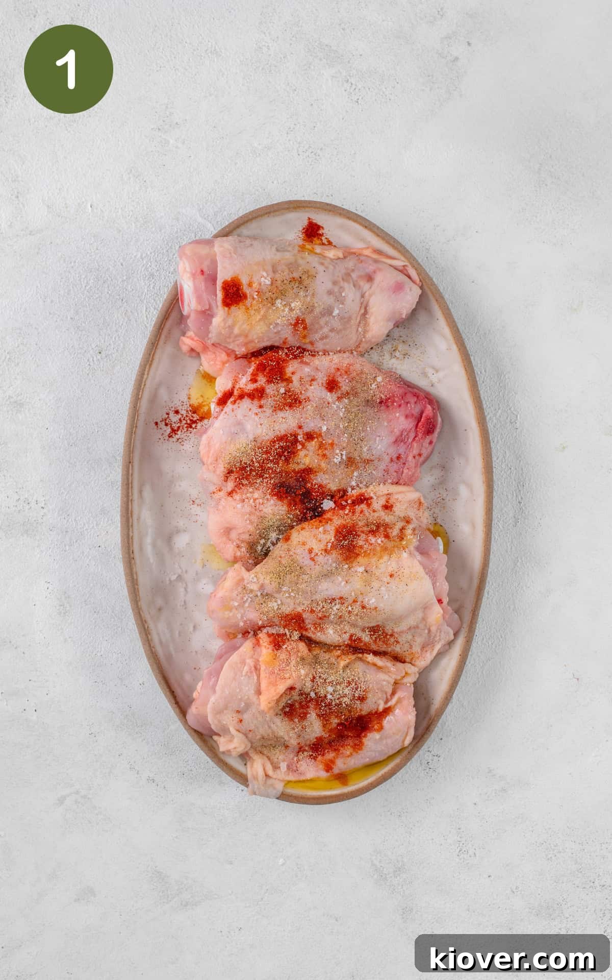 Chicken thighs seasoned with spices in a baking tray, ready for the oven.