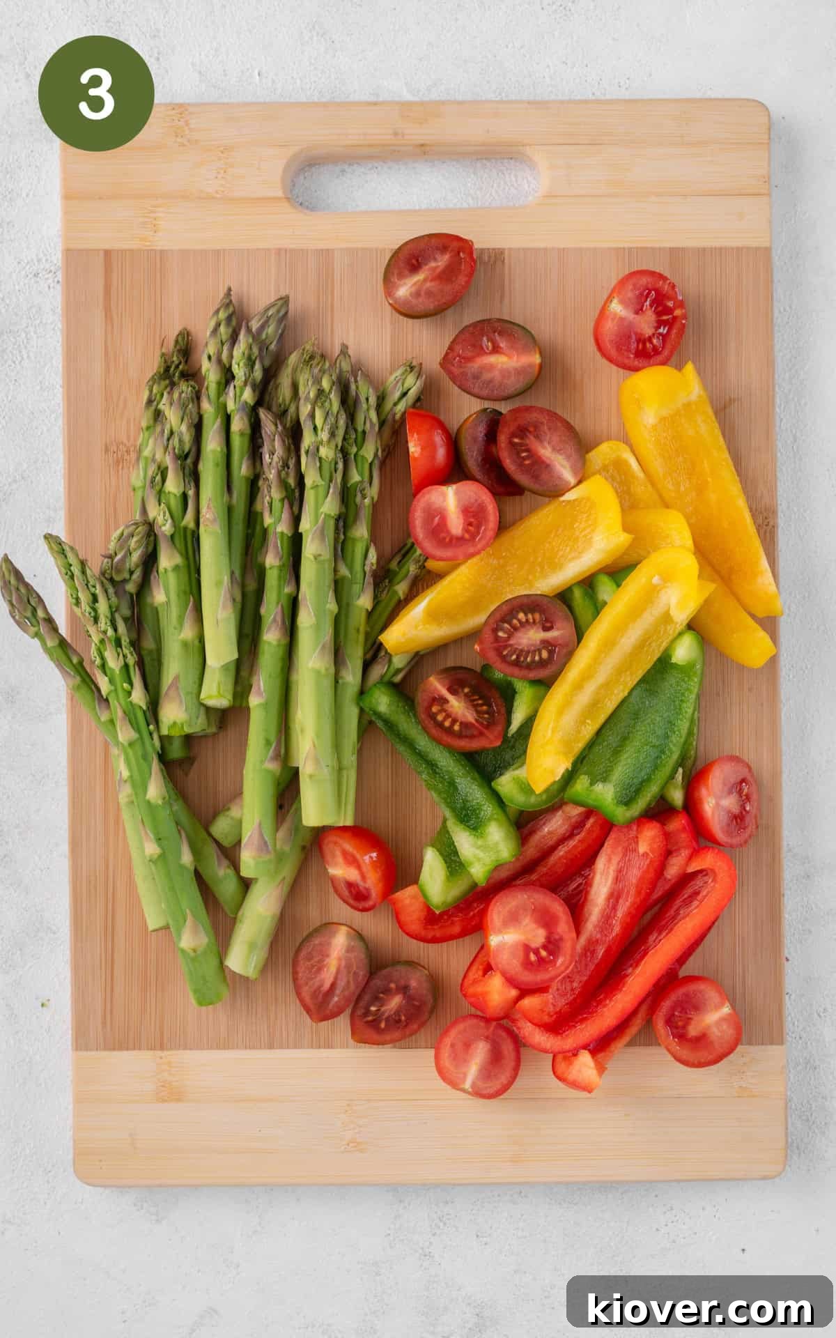 Assorted vegetables including bell peppers and cherry tomatoes on a cutting board.