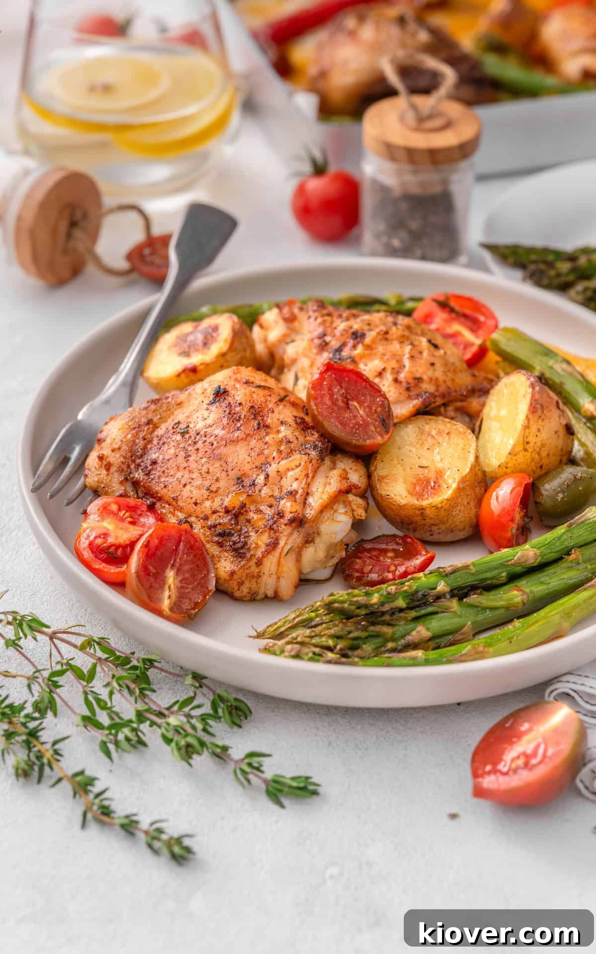 Cooked chicken thighs and roasted vegetables served neatly on a white plate.