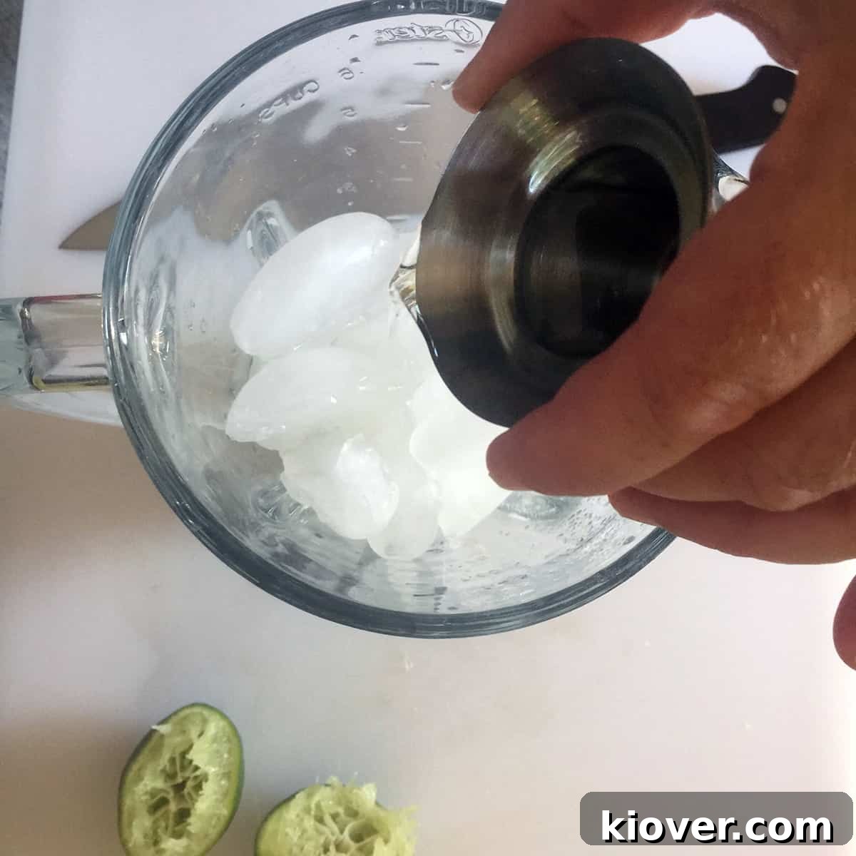 Pour Tequila into Blender A hand pouring tequila into a blender with ice, as part of the margarita preparation.