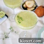 A beautifully presented Frozen Pear and Thyme Margarita, garnished with fresh thyme and a pear slice.