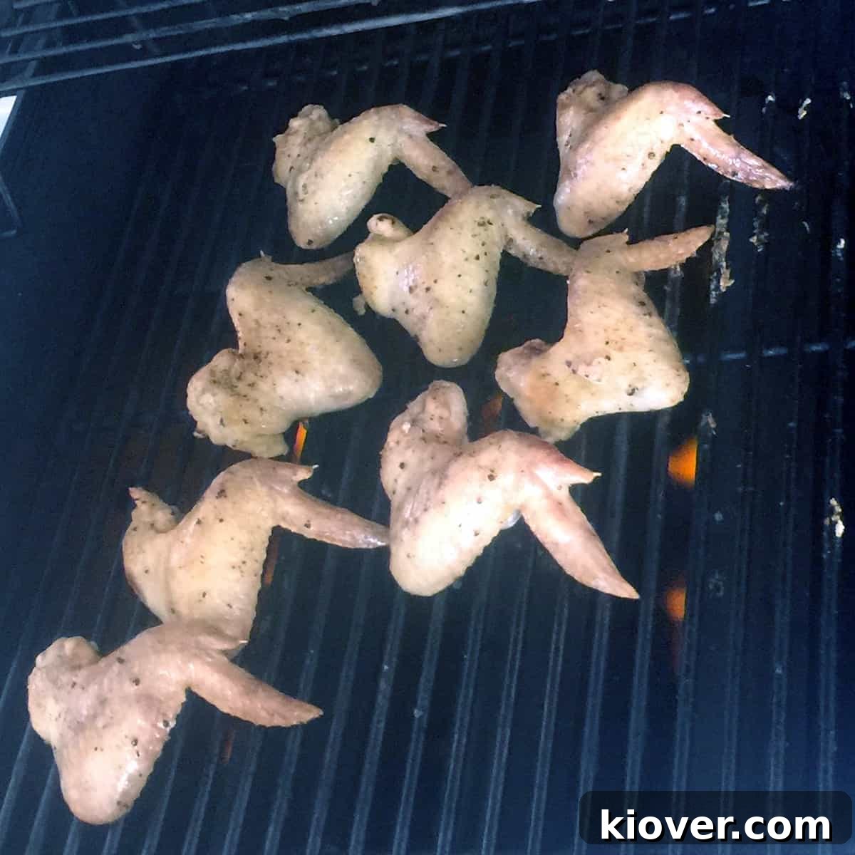 Wings on Grill Eight succulent chicken wings cooking on a hot grill, showing the searing process and developing a crispy exterior.