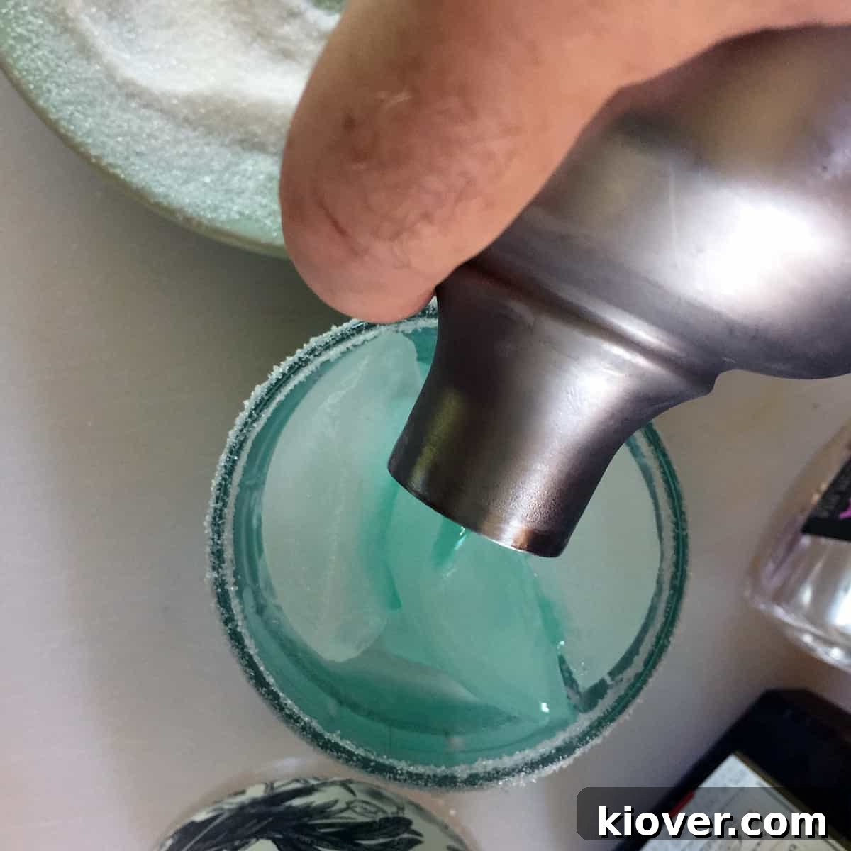 Pouring a finished cocktail into a sugar lined glass.