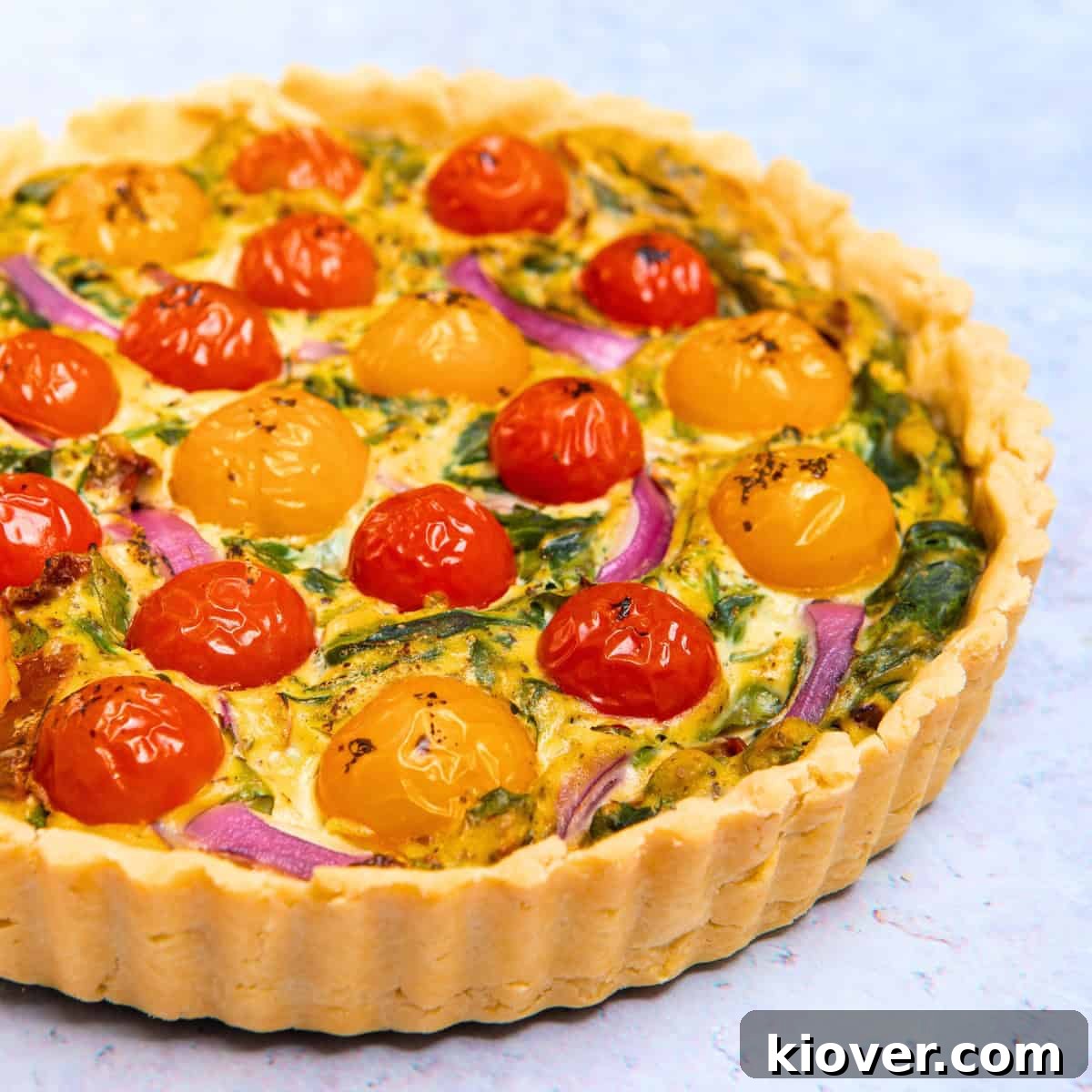 A delicious vegan quiche with a golden, crispy pastry crust, perfectly sliced and served on a elegant marble worktop, ready to be enjoyed.