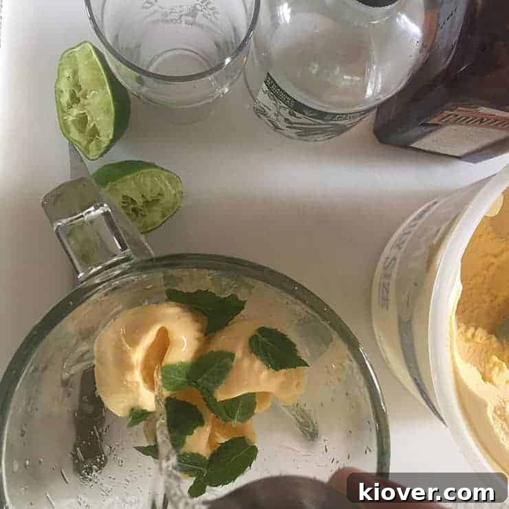 Pouring Tequila into the blender for the drink. A bottle of tequila is being tilted, pouring liquid into a blender filled with ice cream and other ingredients.