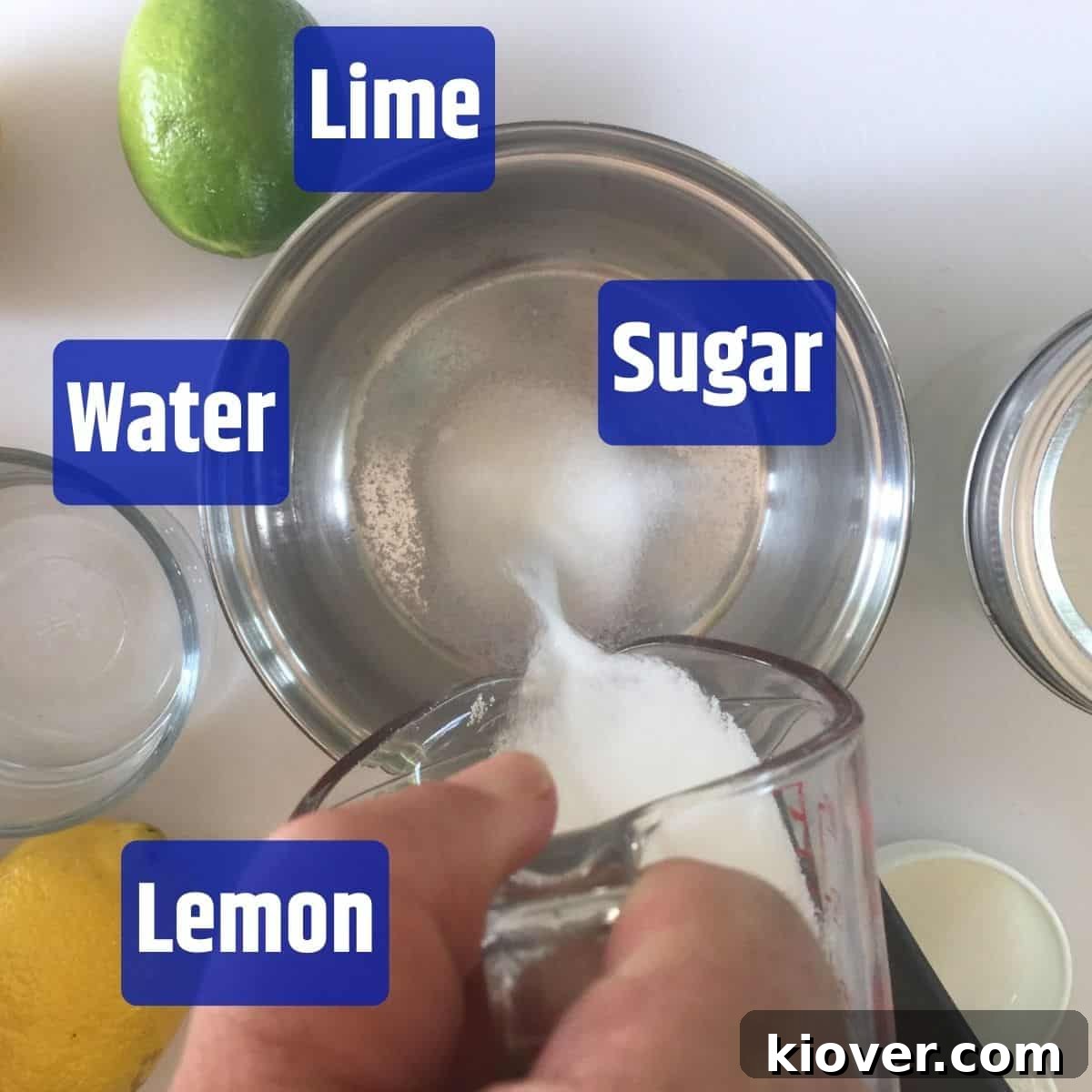 Sweet and Sour Mix Ingredients The simple ingredients for homemade sweet and sour mix: sugar being poured into water in a saucepan, with fresh lemons and limes displayed prominently on a wooden table, emphasizing freshness.