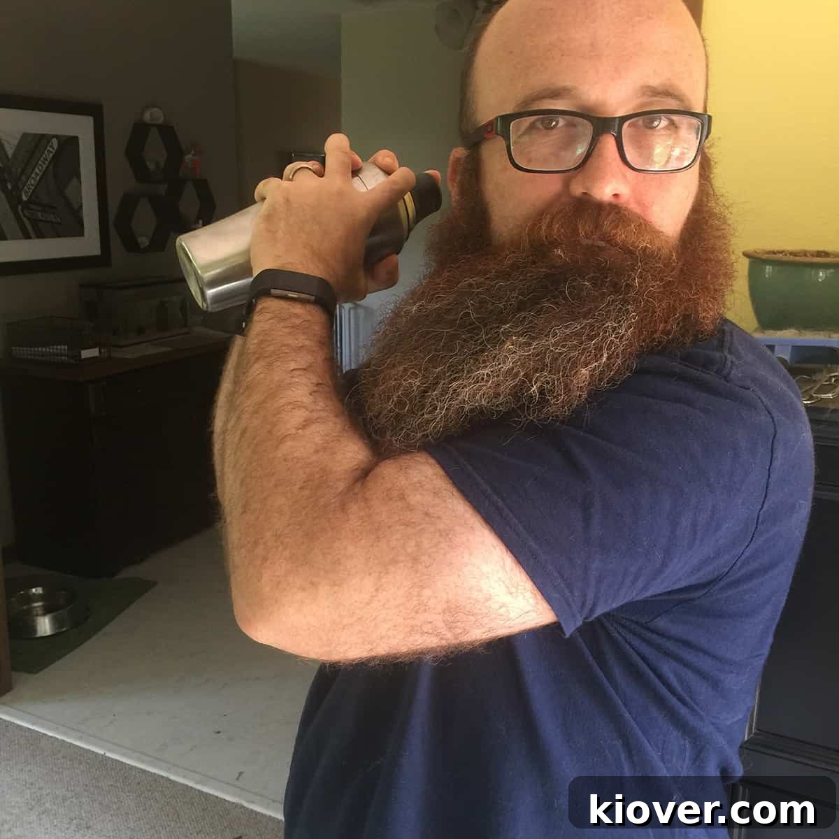 A bearded man expertly shaking a cocktail shaker, illustrating the vigorous motion needed for mixing.