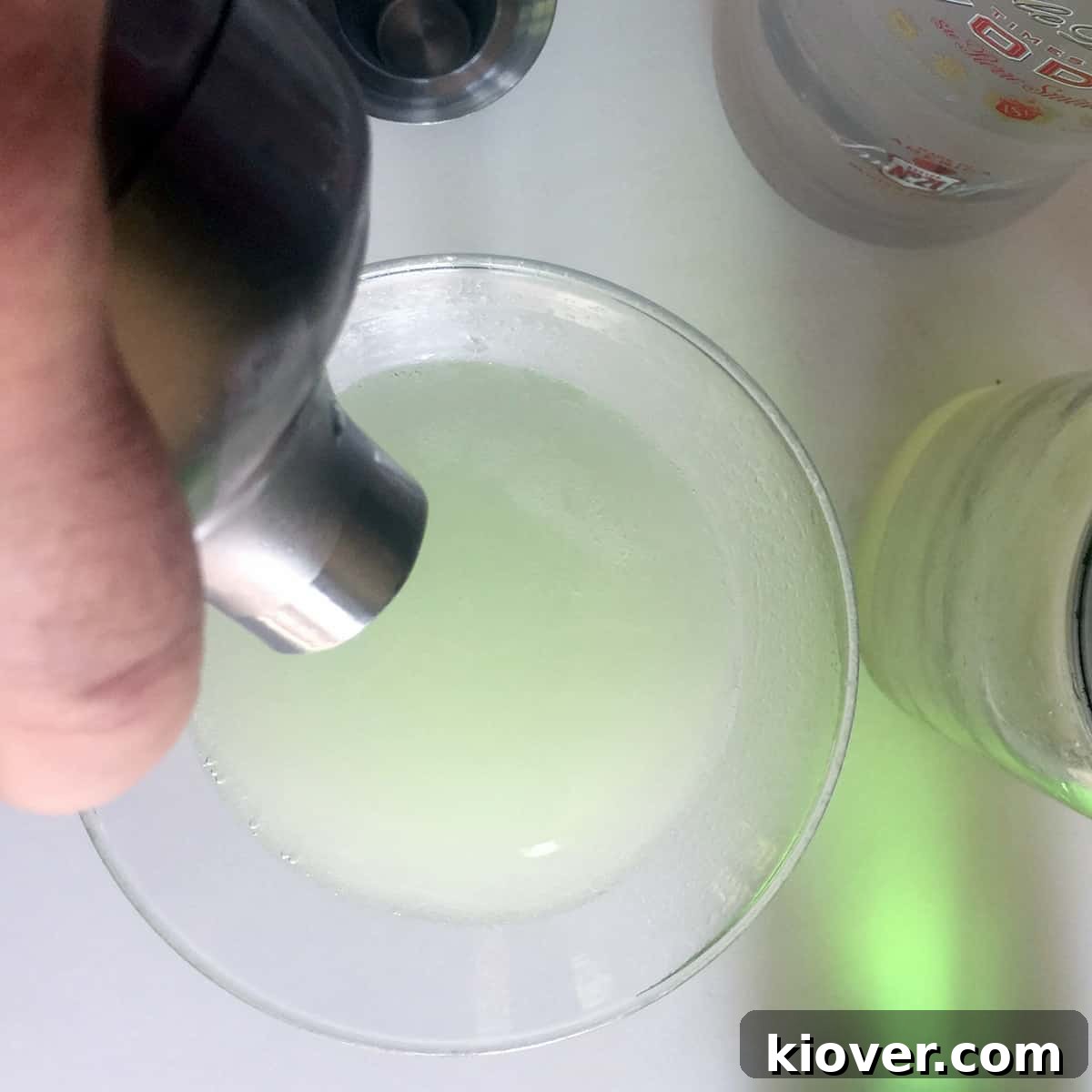 A freshly shaken Appletini cocktail being carefully poured into an elegant martini glass.
