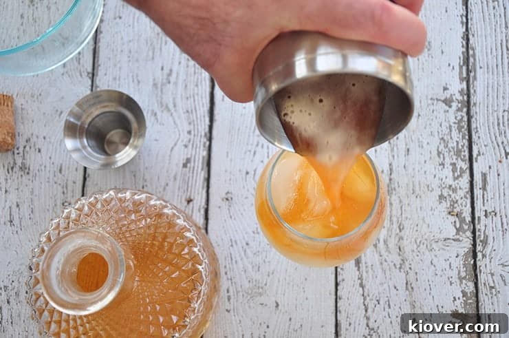 Pouring crisp tonic water into a cocktail glass filled with ice, a key step in making a G&T