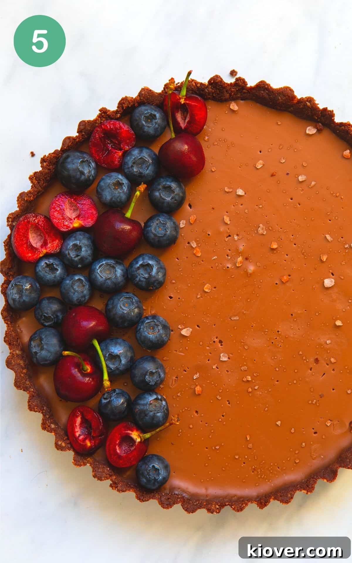 Overhead image of a vegan chocolate tart with fresh berries on top and flakey salts.