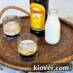 Two Classic White Russian cocktails on a platter with a container of milk and a bottle of Kahlua