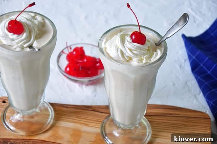 Two milkshakes topped with generous amounts of homemade whipped cream.