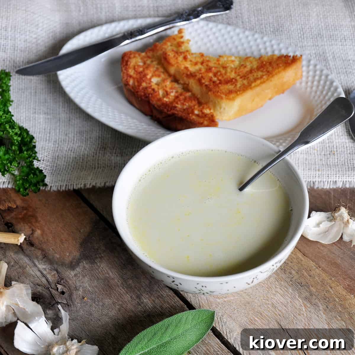 A comforting bowl of Aigo Bouido, French garlic soup, served on a rustic picnic table, garnished with fresh herbs and accompanied by a slice of toasted bread.