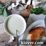 A beautiful bowl of Julia Child's Aigo Bouido, a classic French garlic soup, garnished with fresh herbs and served alongside cheesy toast, inviting a comforting and flavorful meal.