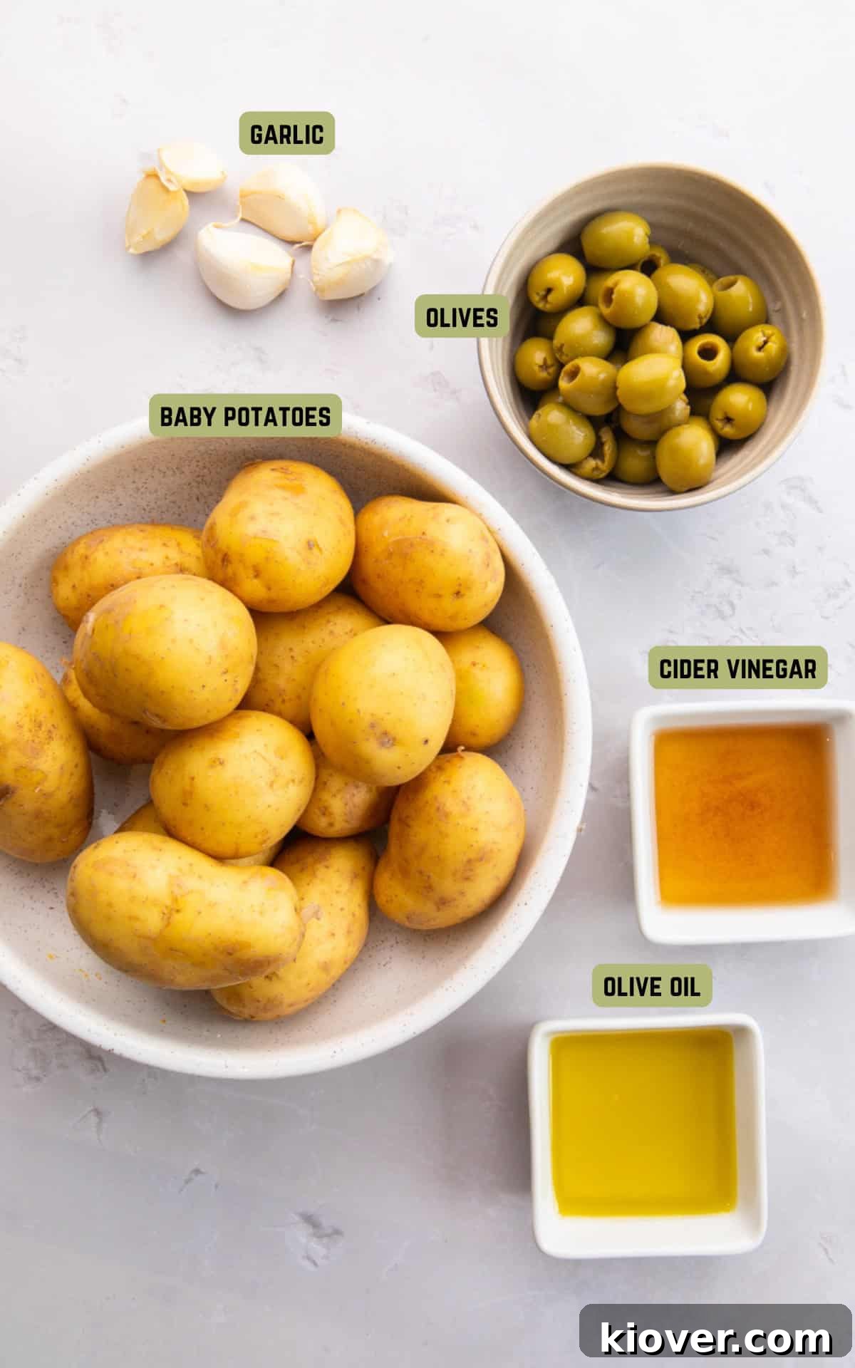 Fresh ingredients laid out on a table to make Smashed Potatoes, including baby potatoes, garlic, olive oil, and cider vinegar.