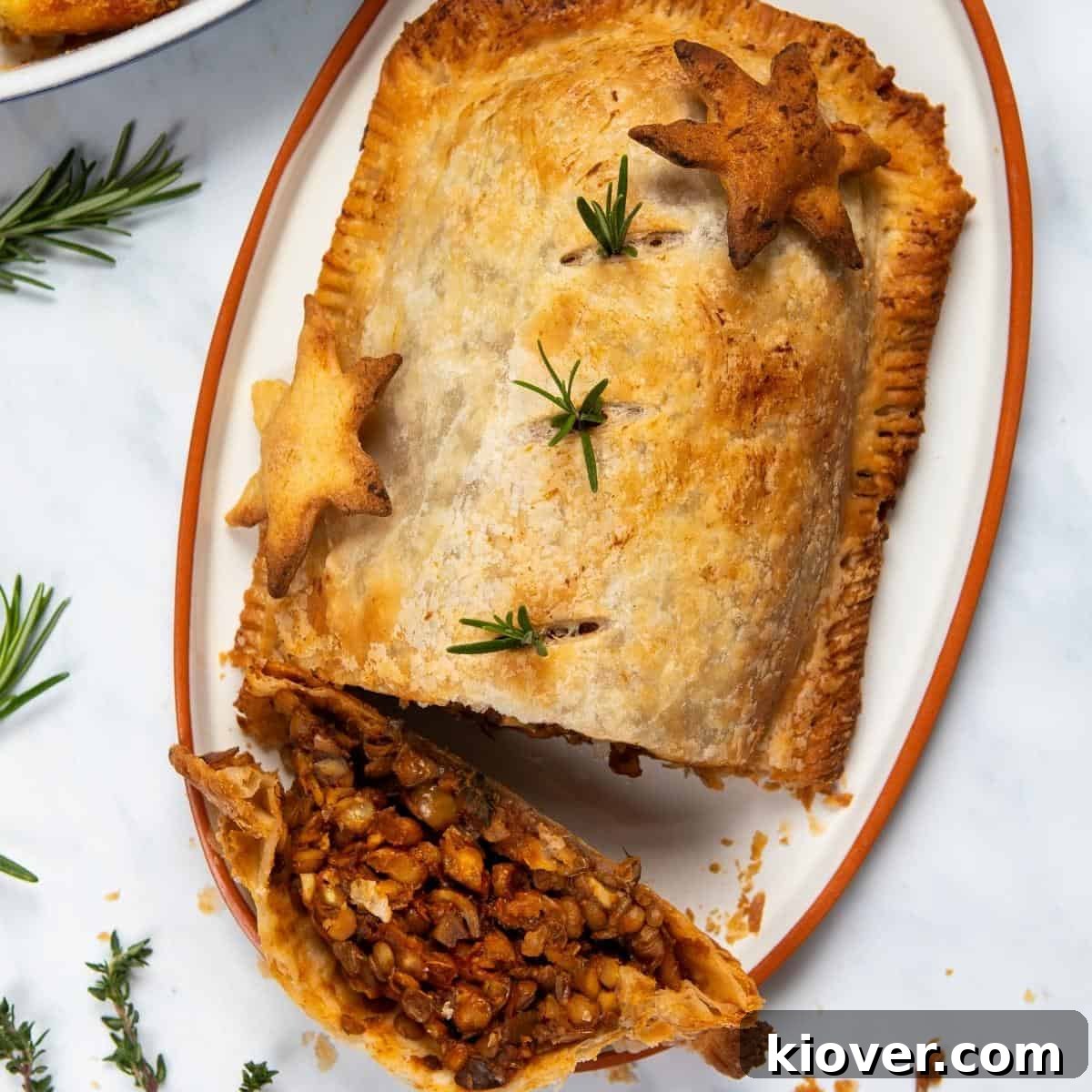 Effortless Lentil Wellington 2 easy lentil wellington on a plate cut open to see the lentil mixture inside, garnished with fresh herbs