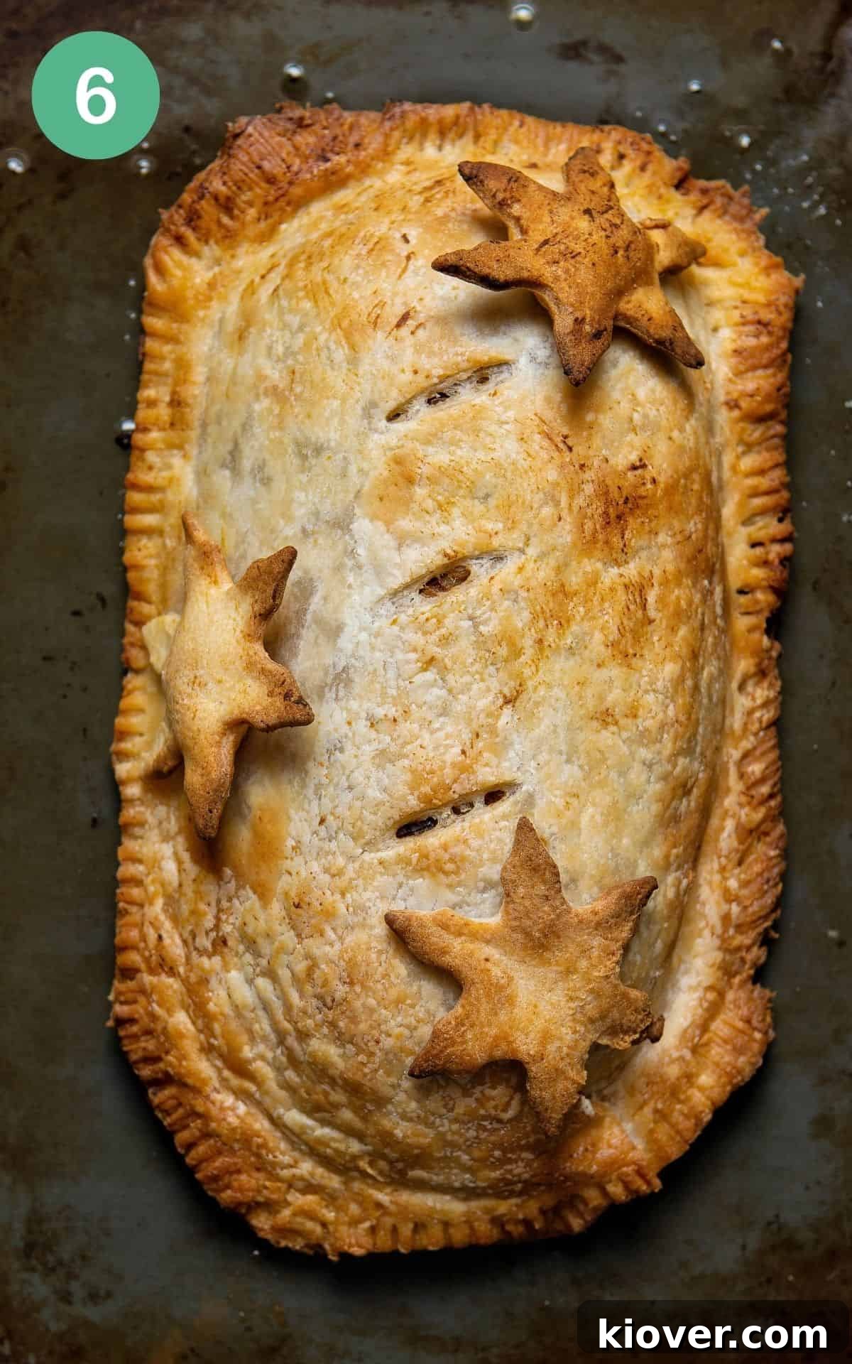 Effortless Lentil Wellington 6 freshly baked vegan wellington on a black baking tray, ready to be sliced