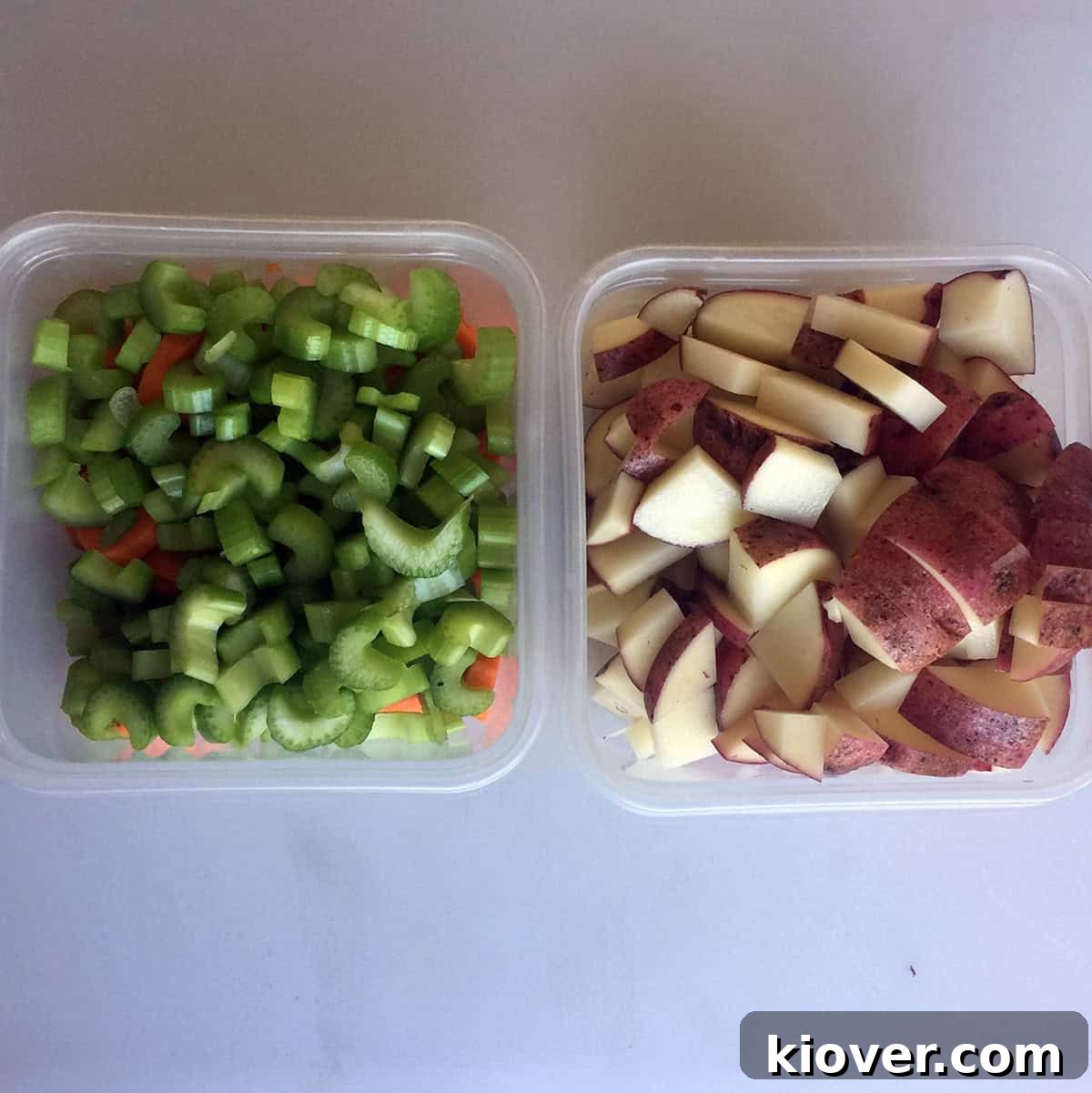 Chopped potatoes in a container, with celery and carrots in another container, ready for cooking.