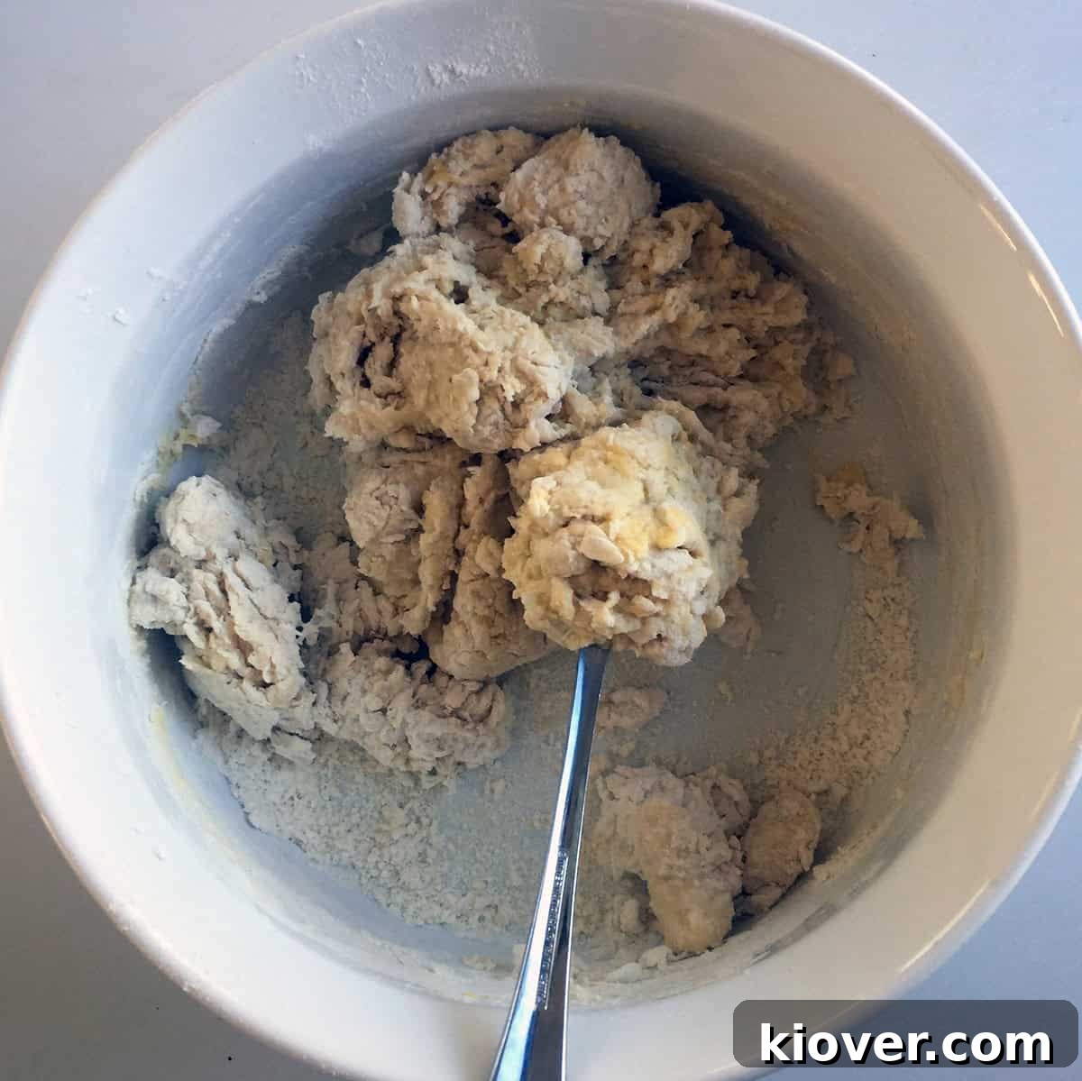 Hands mixing dough in a bowl, showing the process of preparing Knoephla dumplings.
