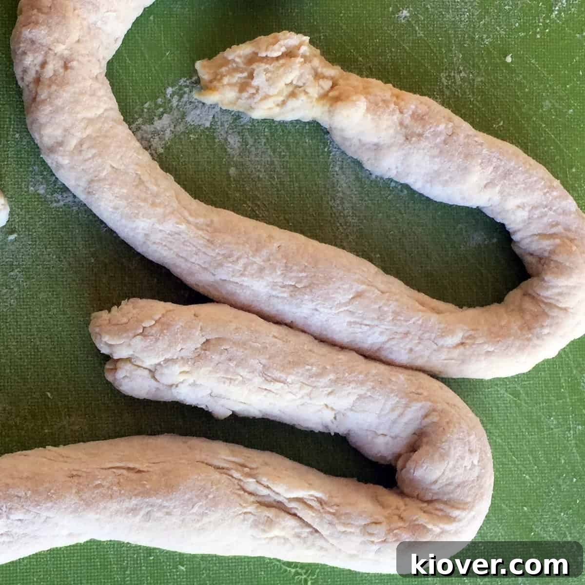 Rolled out Knoephla dough on a cutting board, prepared for slicing into individual dumplings.