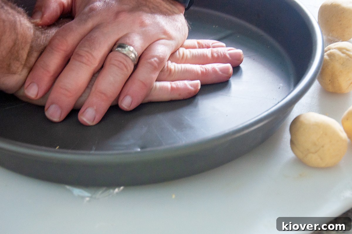 Two hands pressing down on a heavy dish for the purpose of flattening a tortilla.