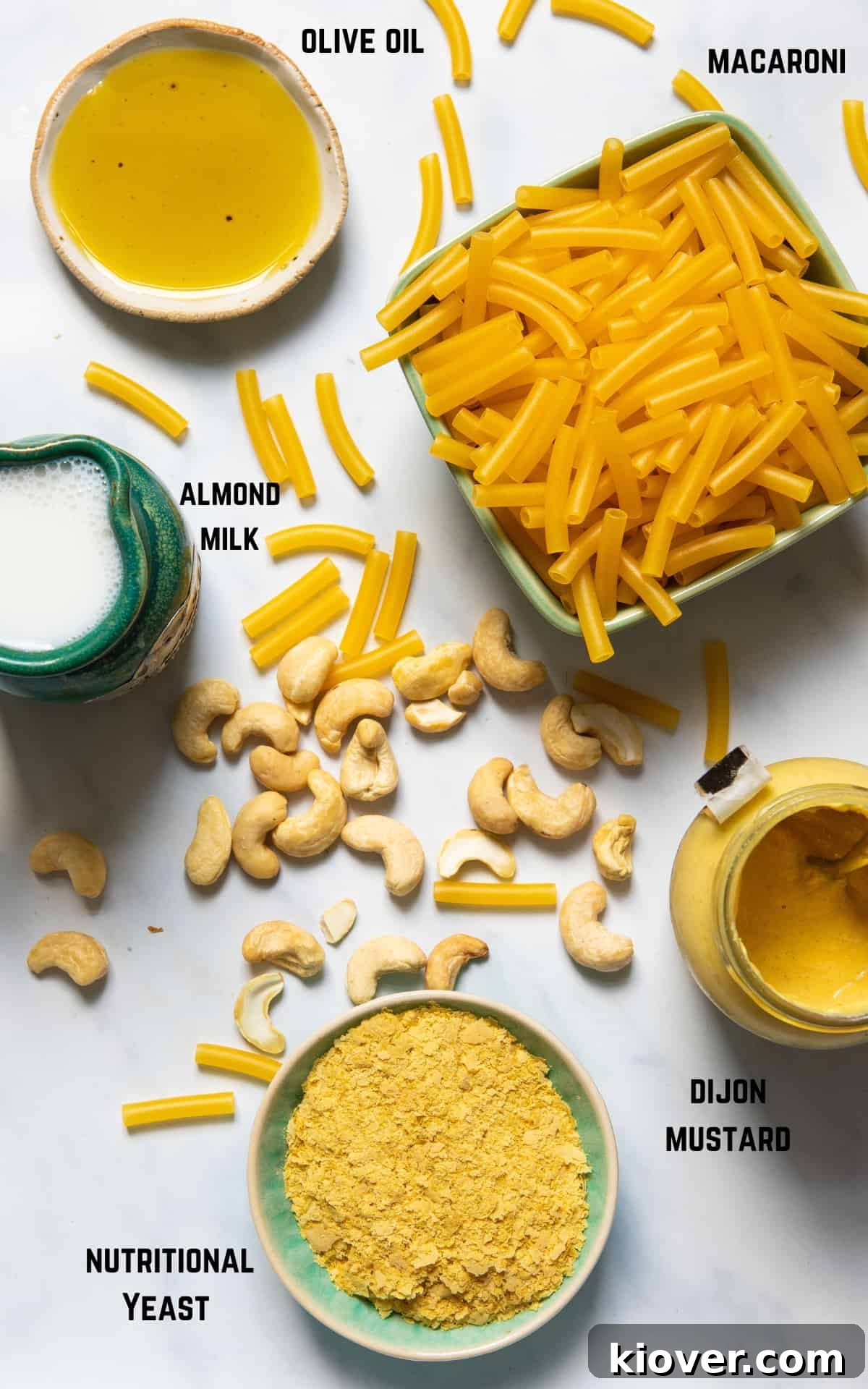 A vibrant display of fresh ingredients laid out on a white marble background, ready to be transformed into a delicious vegan mac and cheese.