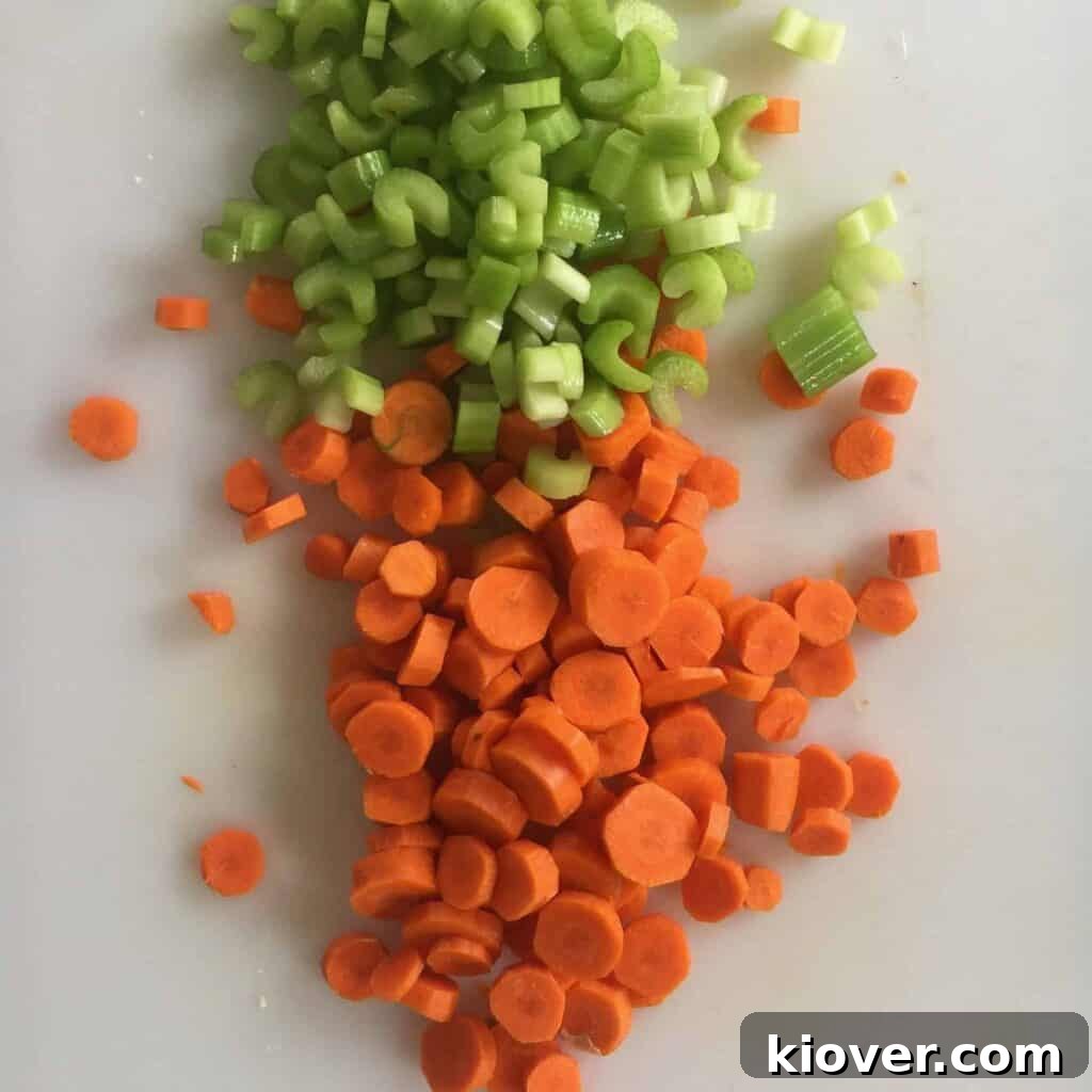 Freshly chopped carrots and celery on a wooden cutting board, ready for the casserole.