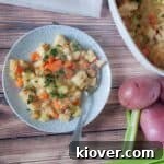 A hearty Knöpfle dumpling casserole served on a rustic picnic table, with fresh potatoes and celery in the background.