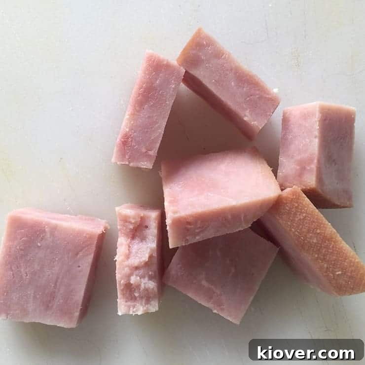Cubes of cooked ham neatly arranged on a wooden cutting board, prepared as the filling for the Klubb dumplings.