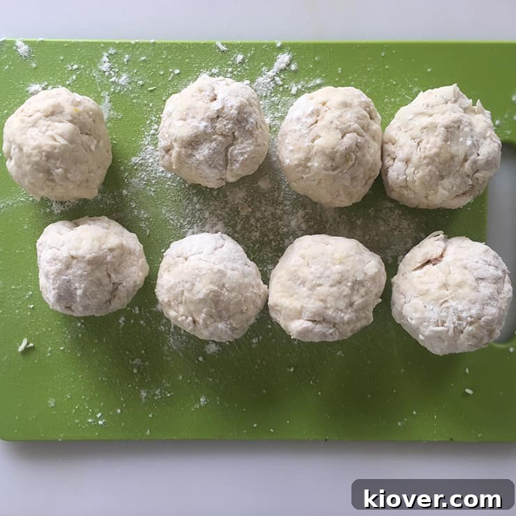 Several perfectly formed, raw Klubb dumplings, each containing a ham cube, resting on a surface before being transferred to simmering water.
