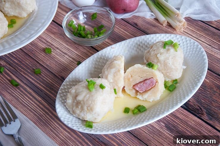 A Klubb Norwegian dumpling sliced in half, clearly showing the cooked ham filling encased within the dense potato dough.