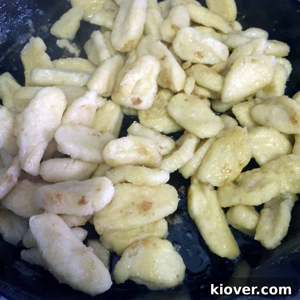 Frying flour dumplings in a skillet with butter after boiling, showing a golden crust.
