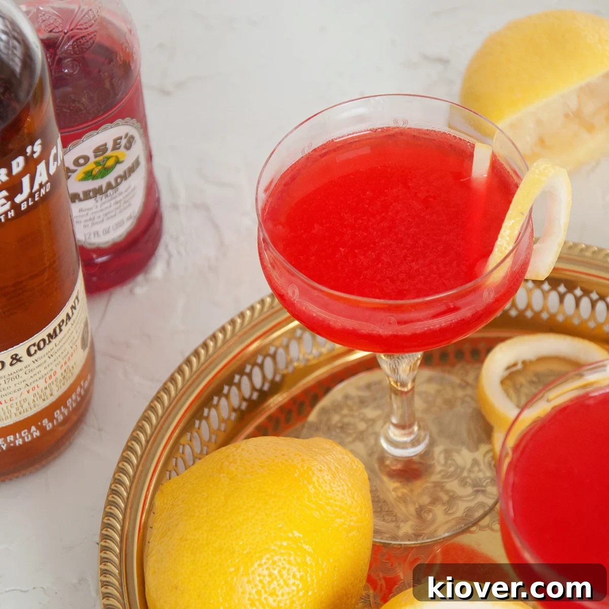 A perfectly crafted Jack Rose cocktail, presented on an elegant gold tray, with the fresh ingredients artistically arranged in the background, ready to be mixed.