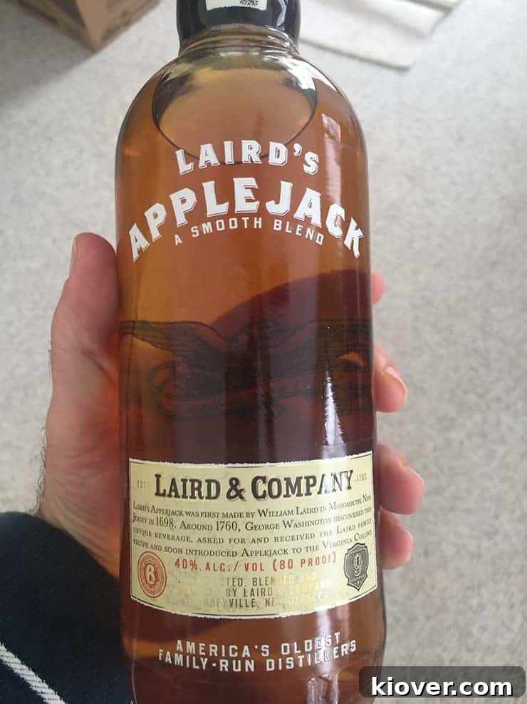 A close-up shot of a bottle of Laird's Applejack, a quintessential ingredient for the classic Jack Rose cocktail, held with care.