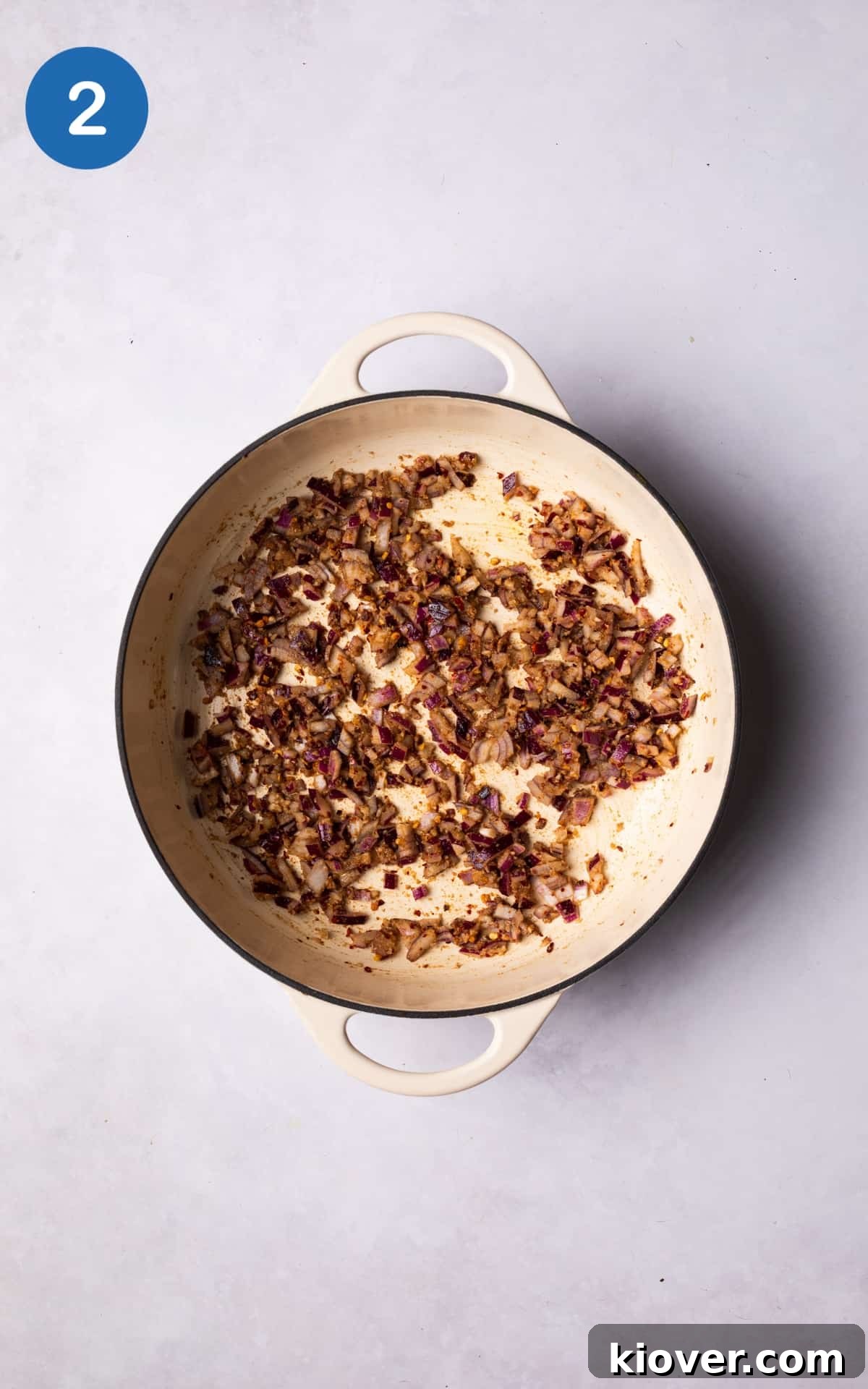 Red onion, garlic paste, ground coriander, and red pepper flakes sizzling in olive oil in a large pot over medium heat.