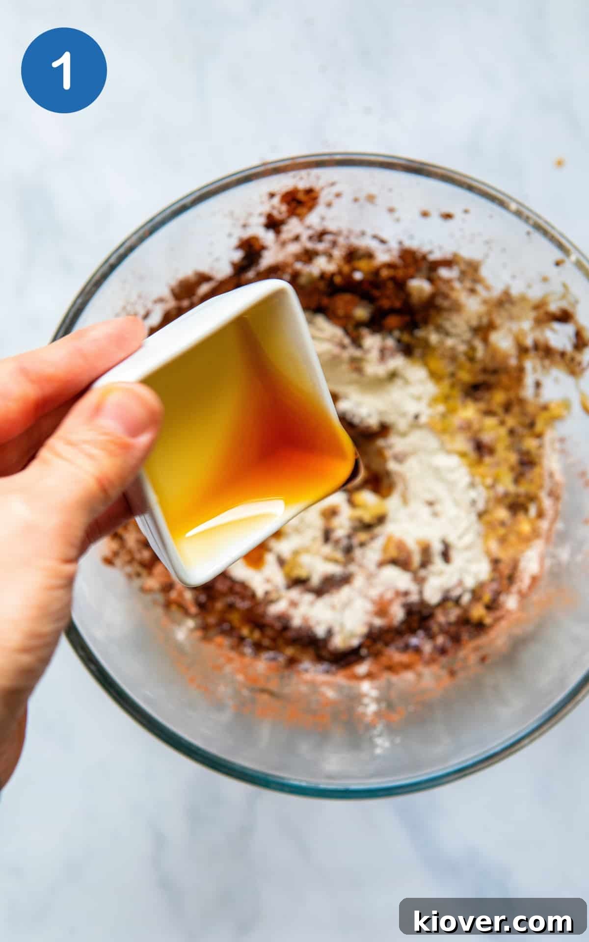 Decadent Gluten-Free Chocolate Treats 4 A hand pouring rich maple syrup into a bowl of dry cookie mix ingredients.