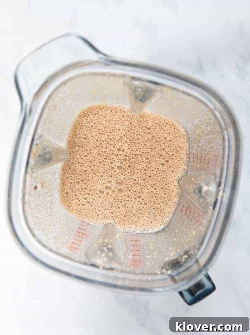 Blending soaked cashews, ripe bananas, dairy-free milk, and cinnamon to create the creamy base for the pudding