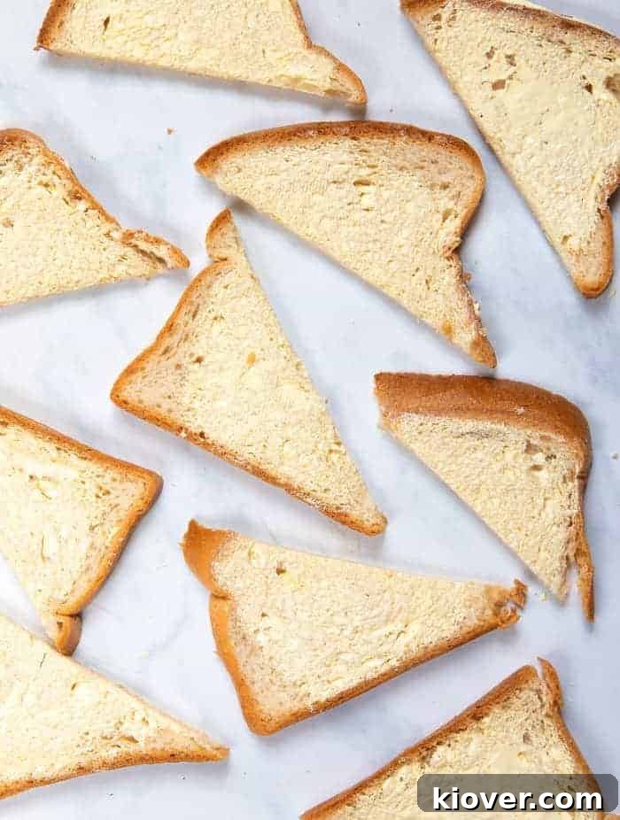 Slices of bread generously spread with vegan butter, ready to be arranged in the baking dish