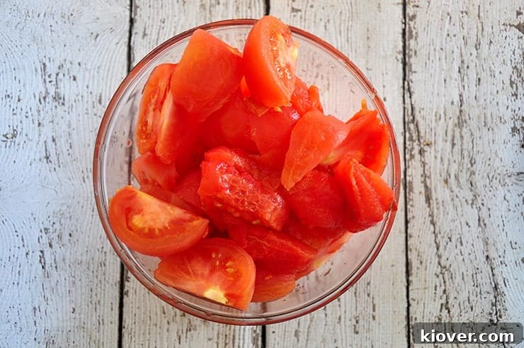 Sectioned tomatoes in a bowl, showing the interior preparation for juicing.