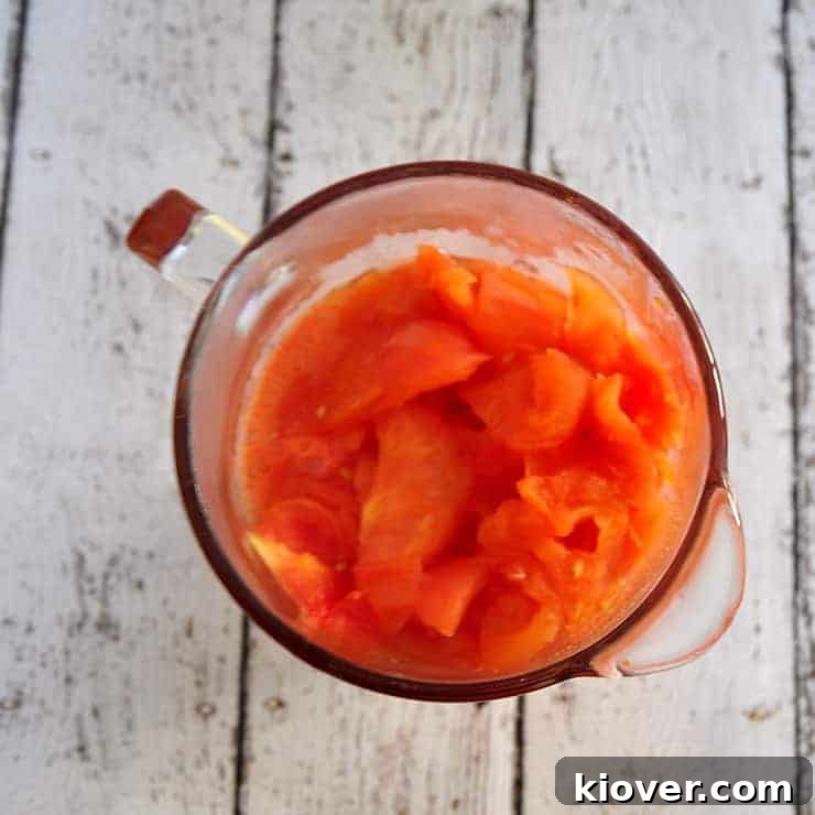 Tomatoes in a blender, capturing the final stage of liquifying.